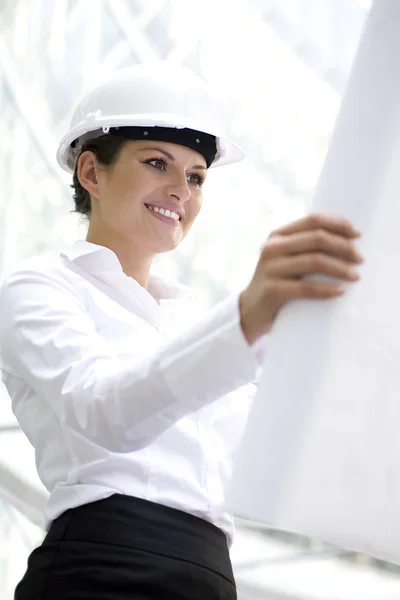 Mulher usando um hardhat segurando planos — Fotografia de Stock