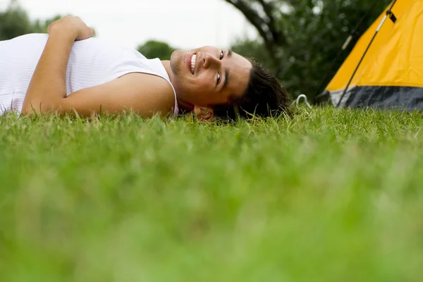 Man lying on grass near tent — Stock Photo, Image