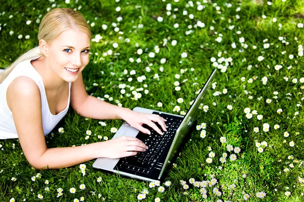 Vrouw opleggen van gras met behulp van laptop Stockfoto