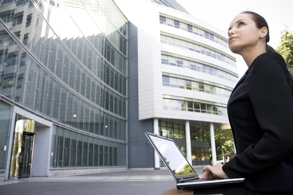 Businesswoman using laptop outside office — Stock Photo, Image