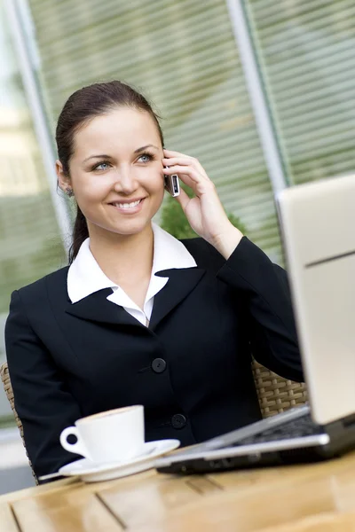 Geschäftsfrau im Freien mit Laptop, telefoniert mit Handy — Stockfoto