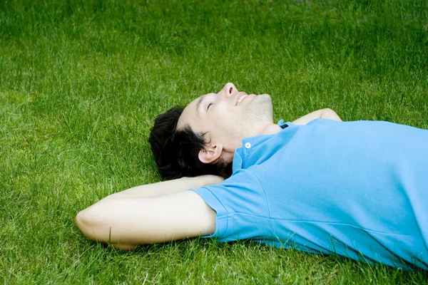 Junger Mann liegt im Gras — Stockfoto