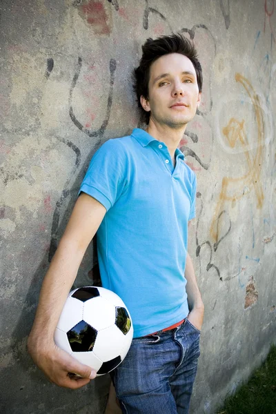 Молодой человек держит футбольный мяч — стоковое фото