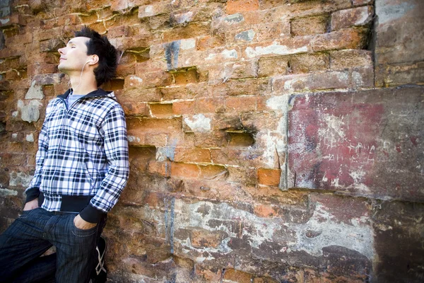 Young man leaning against a brick wall — Stock Photo, Image