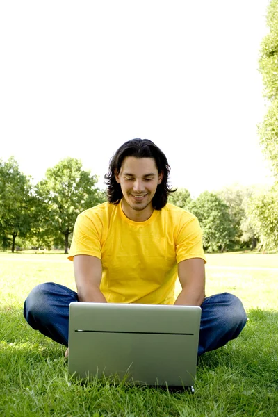 Hombre joven usando el ordenador portátil al aire libre — Foto de Stock