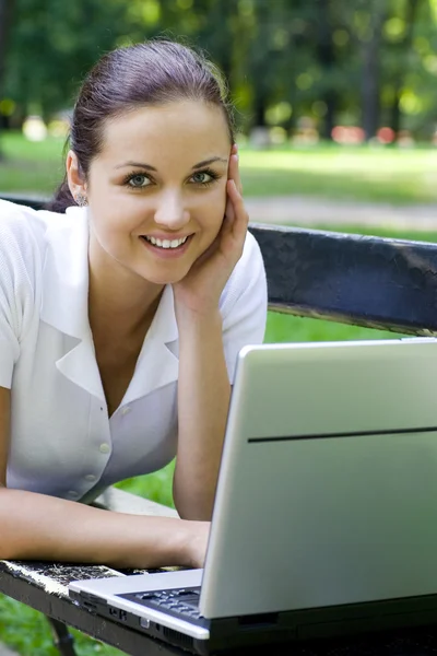 Mulher usando laptop no banco ao ar livre Fotografia De Stock