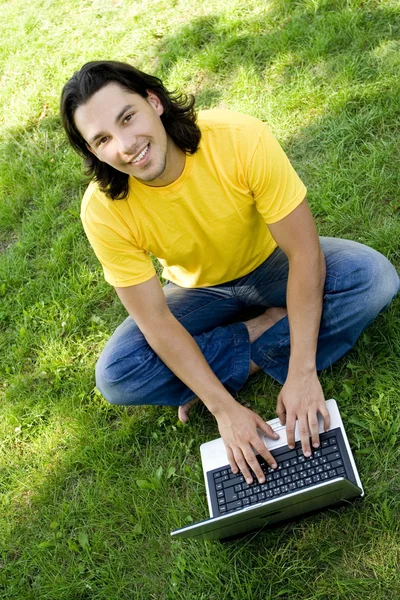 Νεαρός άνδρας, χρησιμοποιώντας φορητό υπολογιστή σε εξωτερικούς χώρους Royalty Free Φωτογραφίες Αρχείου