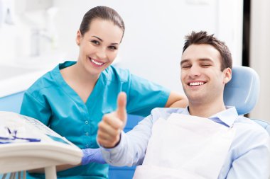Adam dişçi muayenehanesinde baş parmağını kaldırıyor.