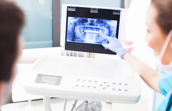 Dentista explicando imagem de raios X para o paciente — Fotografia de Stock