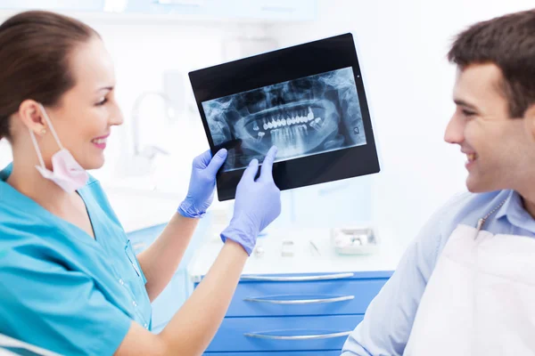 Dentist showing x-rays to patient — Stock Photo, Image