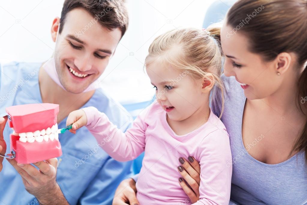 Dentist teaching girl how to brush teeth