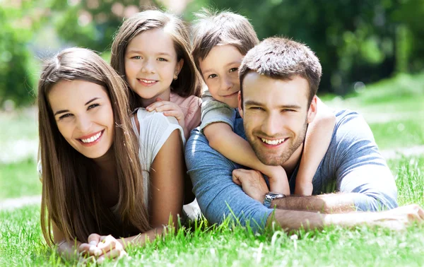 Familjen ligga utomhus på gräs Stockbild