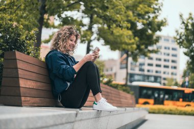 Şehirde cep telefonu kullanan genç bir kadın.