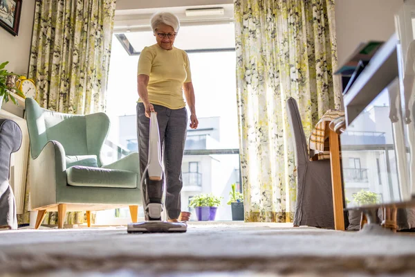 Senior Kvinna Som Använder Dammsugare För Att Rengöra Huset — Stockfoto