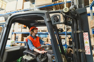 Depoda çalışan genç bir forklift sürücüsü.