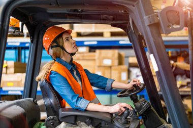Depoda çalışan genç bir forklift sürücüsü.
