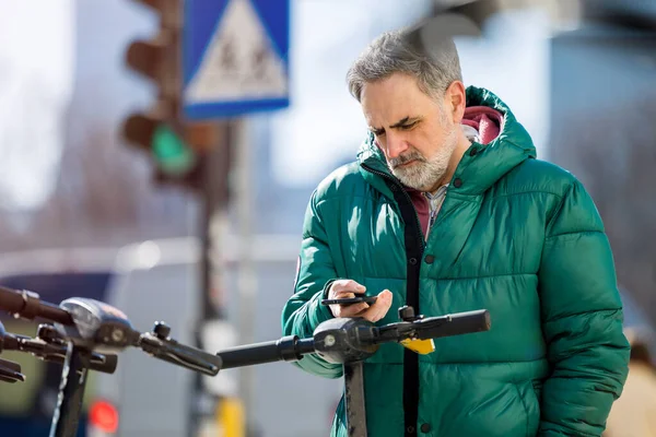 Olgun Adam Akıllı Telefondan Elektrikli Scooter Çalıştırıyor — Stok fotoğraf