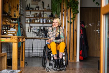 Portrait of an young tattooed woman in a wheelchair at home clipart