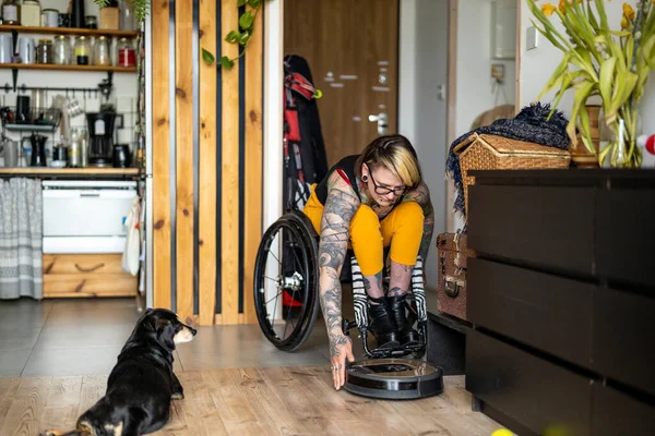 Tekerlekli Sandalyedeki Kadın Evde Akıllı Robot Temizleyici Ayarlıyor — Stok fotoğraf