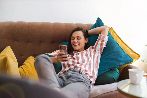 Mujer Joven Feliz Usando Teléfono Móvil Sofá —  Fotos de Stock