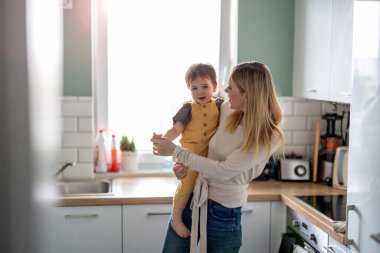 Mutfakta çocuğu olan genç bir anne. 