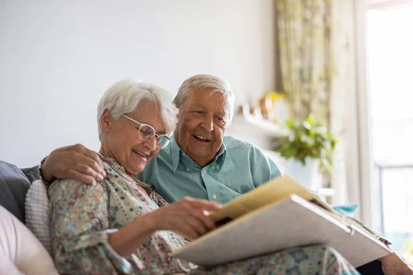 Elderly Couple Looking Photo Album While Sitting Sofa — Stock Photo, Image