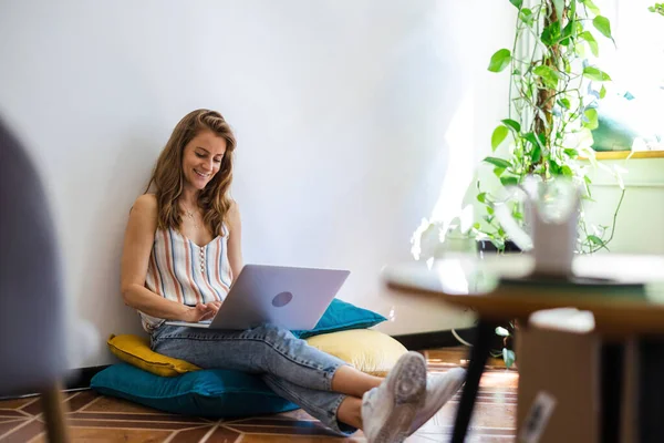 Genç Bir Kadın Evinde Yerde Oturuyor Dizüstü Bilgisayar Kullanıyor — Stok fotoğraf