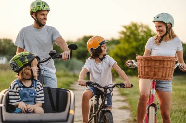 Mutlu aile kırsalda birlikte bisiklet sürüyor.