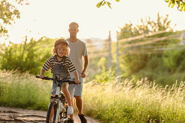 Отец учит сына ездить на велосипеде
