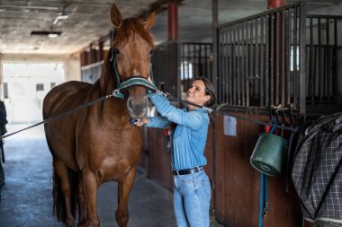 Genç bir kadın atıyla ahırda.