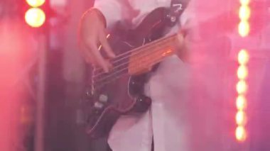 Genç bir adam konserde elektro gitar çalar. Eller yakın plan..