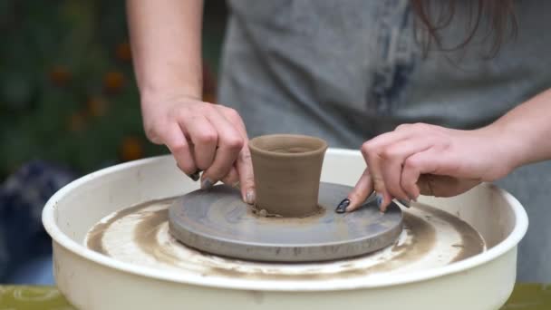 Primer plano de las manos de una niña cortando un producto terminado de una rueda de alfarero con una cuerda. entrenamiento de cerámica. — Vídeo de stock