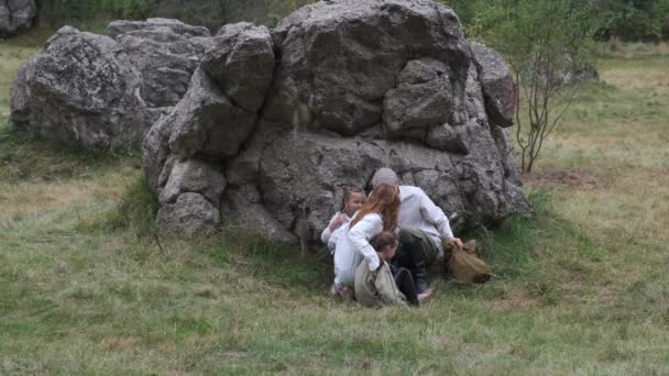 Una familia de refugiados se esconde entre piedras en el campo de batalla. Reconstrucción de la batalla en el territorio del cuartel general del Führer Lobo. — Vídeos de Stock