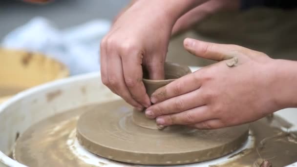 Gros plan des mains des garçons sculptant des plats d'argile sur une roue de potiers. formation poterie — Video