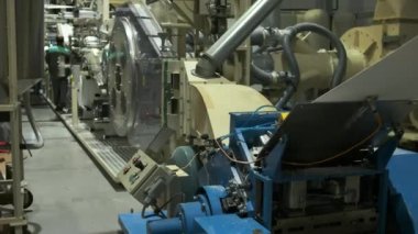 Doğal ahşaptan yapılmış büyük bir selüloz rulosu makinenin üzerinde yavaşça döner. Girişimdeki bebek bezi üretiminin başlangıcı.