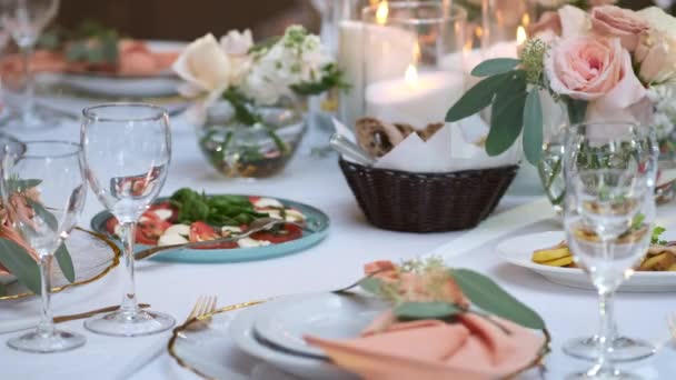 La camarera pone un plato de comida en una mesa festiva bellamente decorada en rosa. — Vídeos de Stock