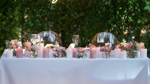 Mesa romántica de vacaciones bellamente decorada con flores rosas y velas encendidas. — Vídeos de Stock
