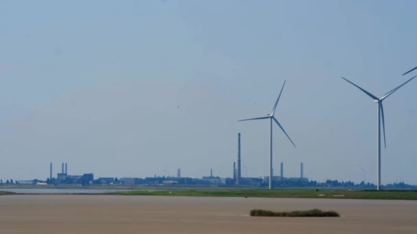 Windkraftanlagen mit Schaufeln zur Stromerzeugung vor dem Hintergrund eines Industrieunternehmens mit Rohren. Globale Ökologie. Das Konzept der sauberen Energie. — Stockvideo