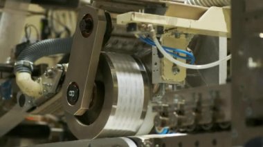 Bebek bezi üretimi için bir fabrika. Bebek bezlerinin dış katmanı makinede yapılır. Büyük davul yakın planda döner..