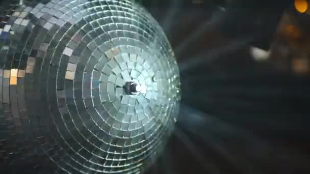 Зеркальный диско-шар крупным планом вращается на вечеринке. От него отражаются лучи разных цветов. — стоковое видео
