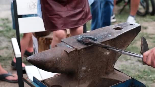 閉じる馬蹄の鍛造のアップ 祭りの鍛冶屋は ハンマーで鉄の馬蹄形を作るために女の子を教えています 鍛冶屋だ — ストック動画