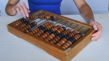 Yaşlı ahşap abaküse güvenen bir kızın ellerine yakın çekim. Genç bir kızın ellerinde vitiligo hastalığı, cilt bölgelerinde depigmentasyon.
