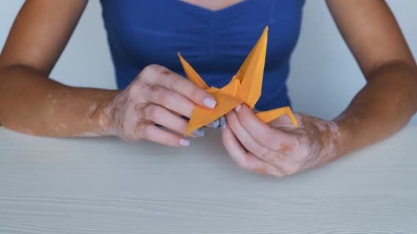 Крупный План Рук Девушки Витилиго Делает Бумажный Оранжевый Кран Кожные — стоковое видео