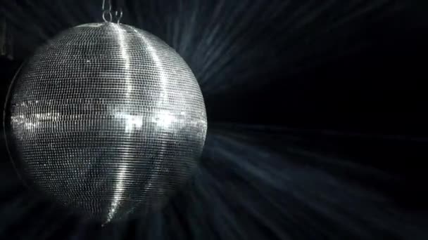 Bei einer Party dreht sich eine verspiegelte Discokugel. Silbrige Lichtstrahlen werden im Rauch reflektiert. — Stockvideo