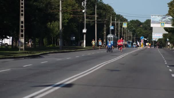 ウクライナ Vinnitsa 2021年8月24日 未確認の人々が市内マラソンの通りを走っています 隣に車椅子の男が乗っている — ストック動画