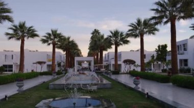 Mısır, Sharm el-Sheikh, 2021 civarı. Güneşli bir günde otelde palmiye ağaçları ve fıskiyesi olan merkez sokak..