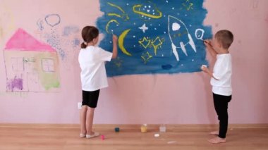 Küçük bir kız ve bir oğlan pembe bir duvar kağıdının üzerindeki bir apartmanın duvarına roket çiziyor. Mutlu bir çocukluk ve sanat aşkı kavramı..