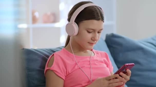 Una Adolescente Está Sentada Una Habitación Blanca Sofá Con Auriculares — Vídeos de Stock