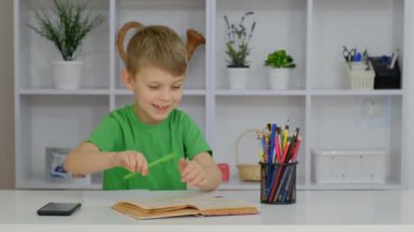 Küçük bir çocuk odasında oturuyor ve ödevini yapıyor..