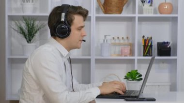 Bilgisayarında kulaklıkla oturan genç bir adam çağrı merkezindeki bir müşteriyle konuşuyor..